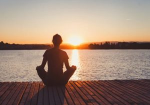 a person looks over a sunset while meditating and experiencing holistic programs