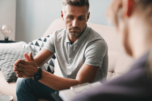 A man participates in a medication-assisted treatment program. He sits across from a therapist.