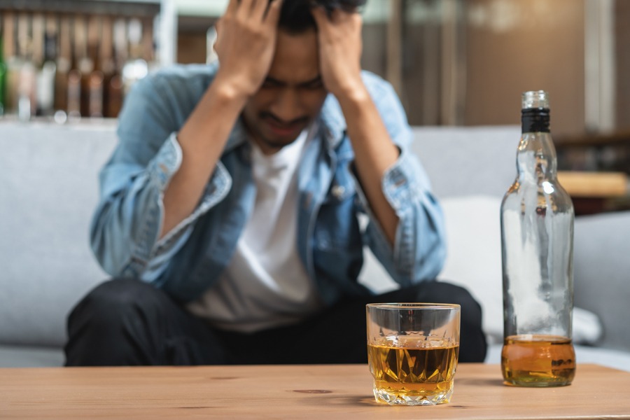 a man with hands on head with alcohol on table